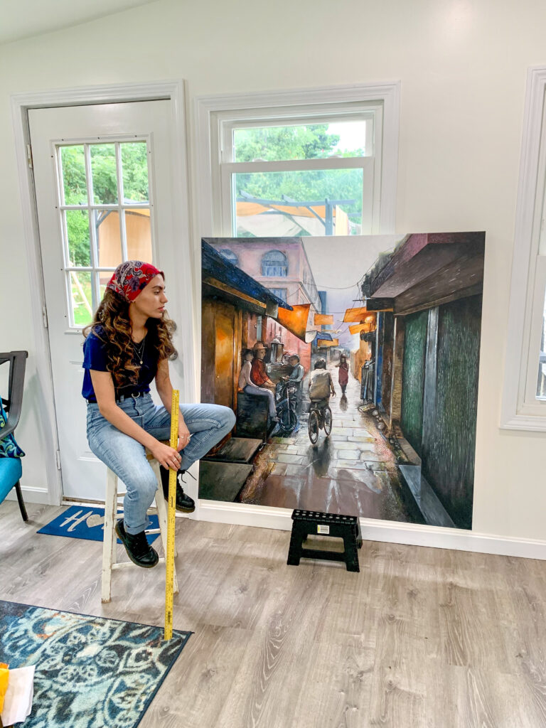 Fatimah in studio with painting. 